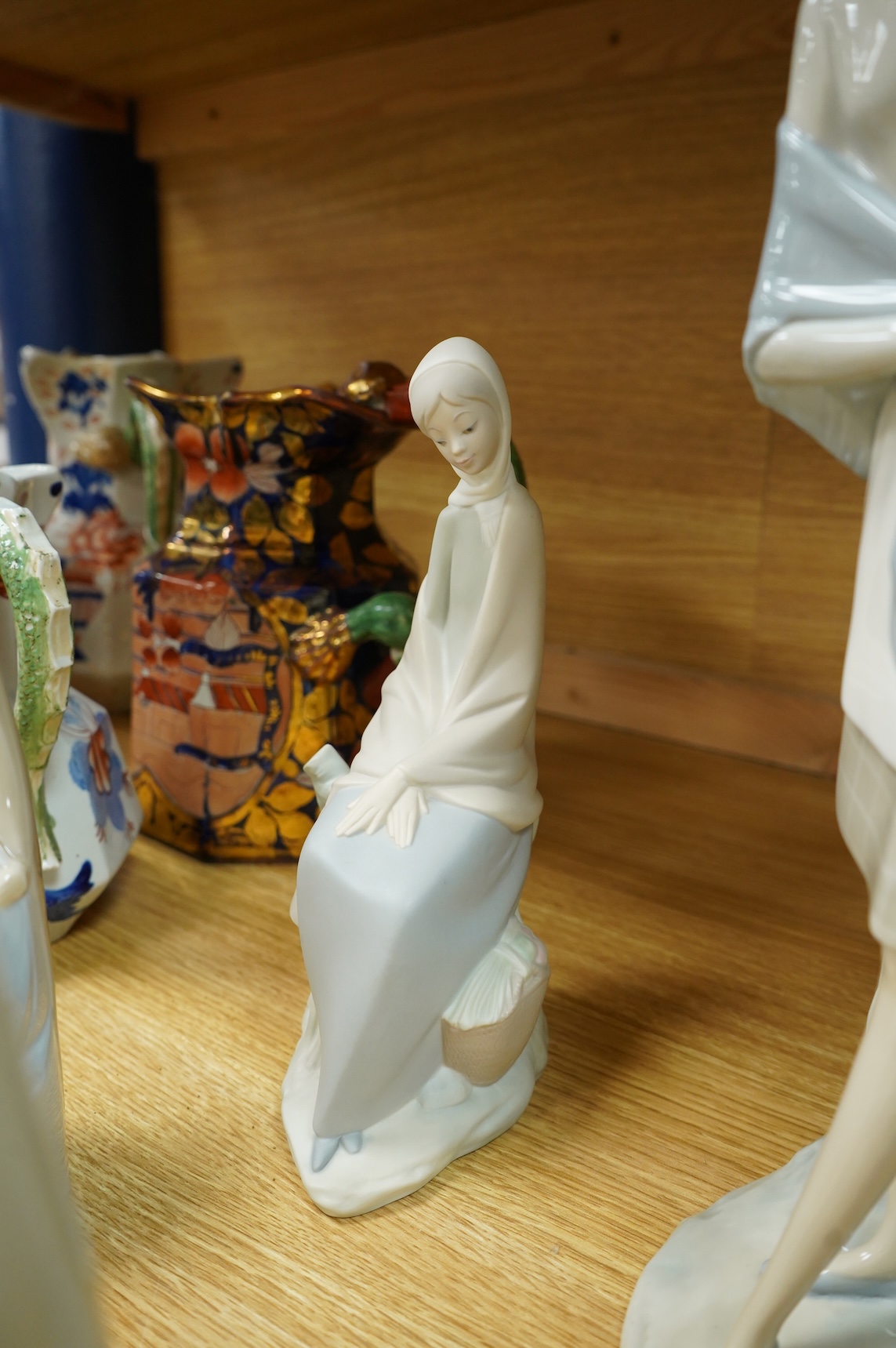 A group of Lladro figures: Tramp with violin, Bust of Mary Magdalene, Holy family, Girl with child, Young Shepherds, Girl with basket, girl with jug
